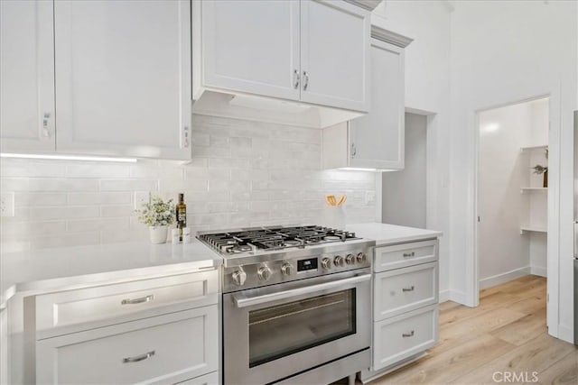 kitchen featuring white cabinets, stainless steel gas range, tasteful backsplash, and light hardwood / wood-style flooring