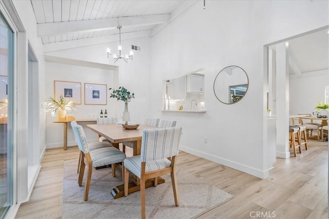 dining room featuring light hardwood / wood-style floors, sink, a chandelier, and vaulted ceiling with beams