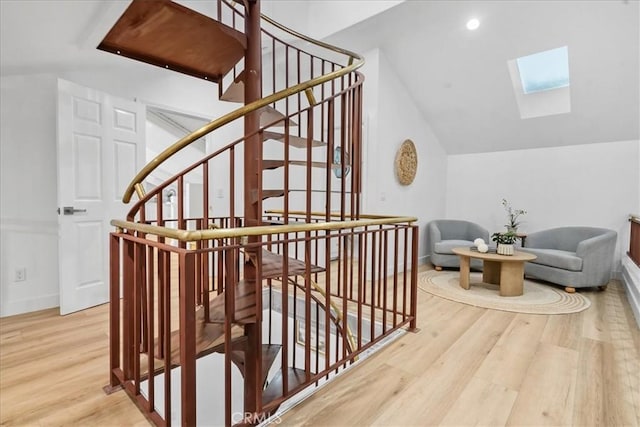 interior space featuring vaulted ceiling with skylight and hardwood / wood-style flooring