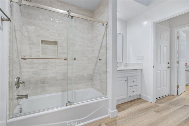 bathroom with bath / shower combo with glass door, wood-type flooring, and vanity