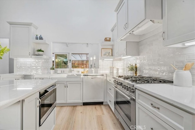 kitchen featuring dishwasher, high end range, oven, light hardwood / wood-style floors, and white cabinetry