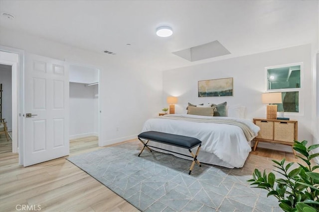 bedroom with a closet, a spacious closet, and light hardwood / wood-style floors