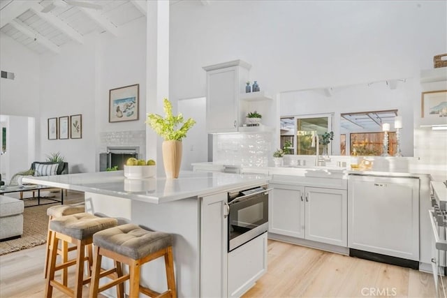 kitchen featuring dishwasher, white cabinets, a breakfast bar, and beamed ceiling