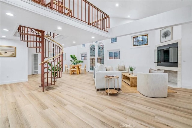 living room featuring a towering ceiling and light hardwood / wood-style flooring