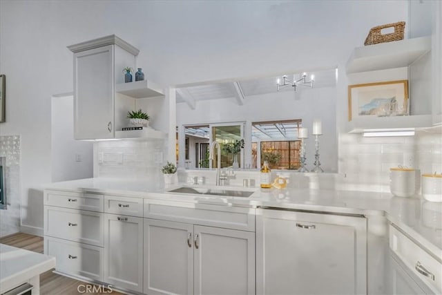 kitchen with tasteful backsplash, a fireplace, beam ceiling, sink, and light wood-type flooring