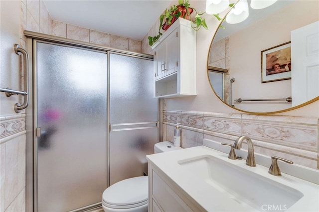 bathroom with toilet, tile walls, a shower with door, and vanity