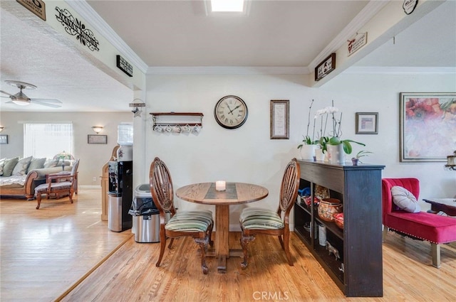 dining room featuring ceiling fan, wood-type flooring, a textured ceiling, and ornamental molding