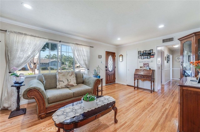 living room featuring a textured ceiling, light hardwood / wood-style flooring, and crown molding