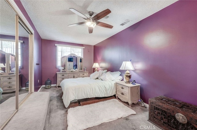 bedroom featuring ceiling fan, a closet, light carpet, and a textured ceiling