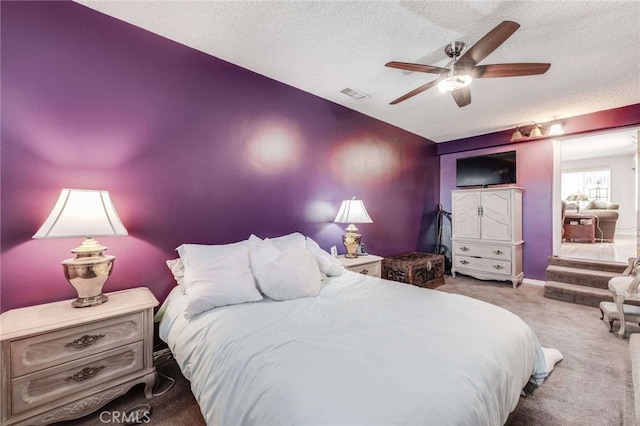 carpeted bedroom with ceiling fan and a textured ceiling