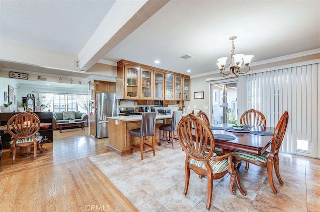 dining area featuring crown molding, a chandelier, and light hardwood / wood-style floors