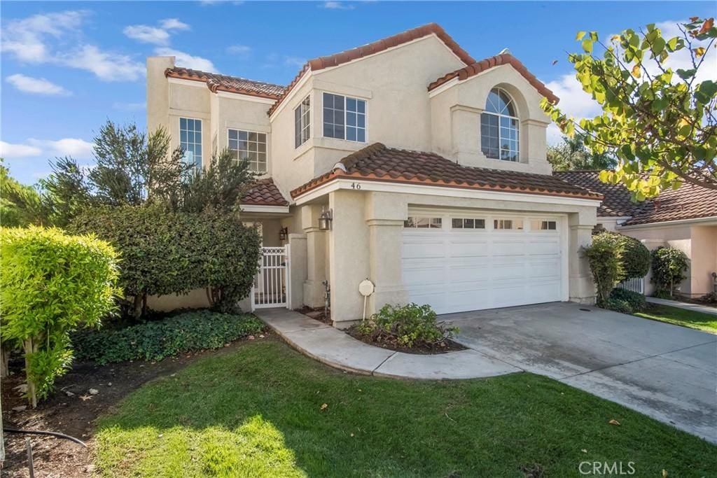 mediterranean / spanish-style home with a garage and a front lawn