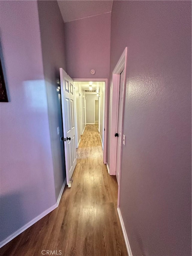 hall featuring a towering ceiling and light wood-type flooring