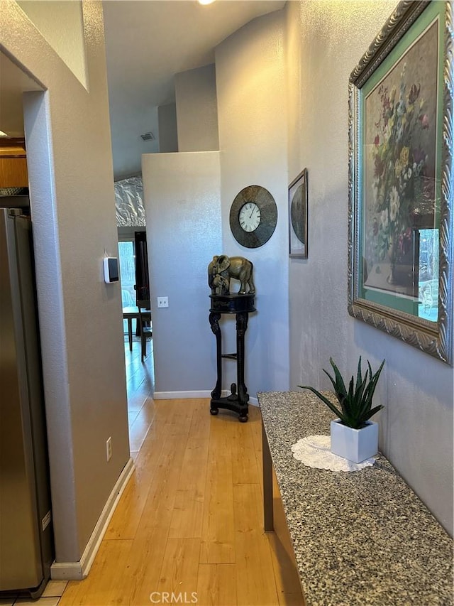 hallway featuring vaulted ceiling and light hardwood / wood-style flooring