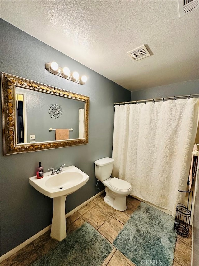 bathroom with tile patterned flooring, a textured ceiling, and toilet