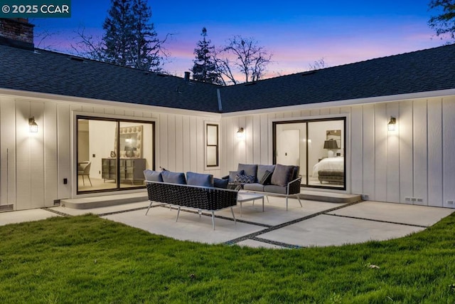 back house at dusk with a yard, an outdoor hangout area, and a patio