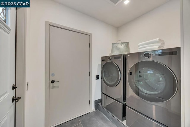 laundry room with washer and clothes dryer and dark tile patterned floors