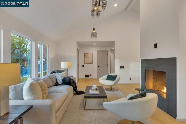 living room featuring beam ceiling, high vaulted ceiling, and light hardwood / wood-style floors