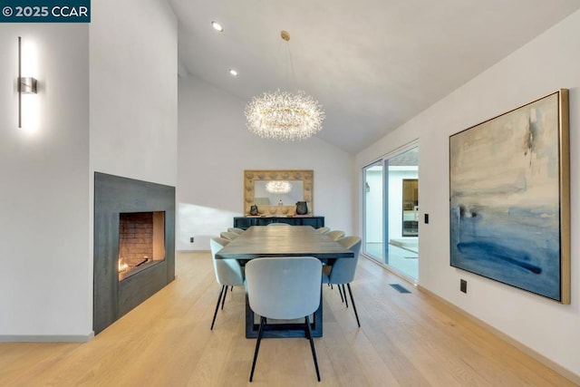 dining area featuring light wood-type flooring, lofted ceiling, and a notable chandelier