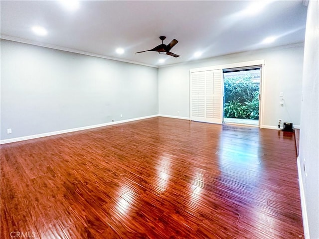 empty room with a ceiling fan, crown molding, baseboards, and wood finished floors