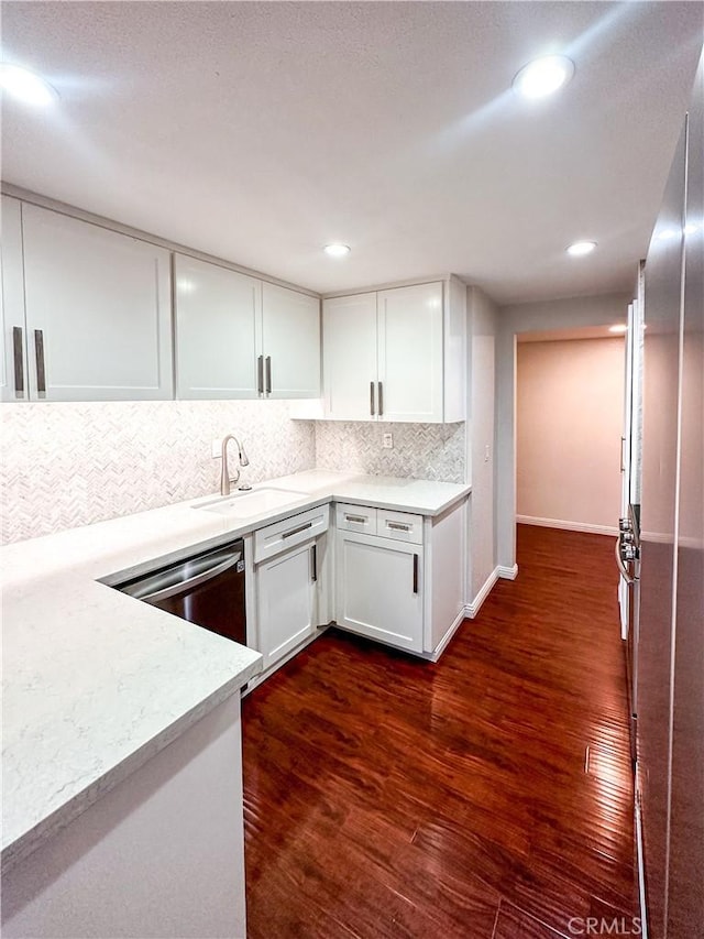 kitchen featuring white cabinets, dark wood-style flooring, a sink, light countertops, and backsplash