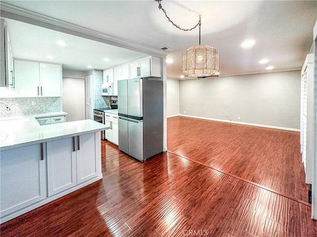 kitchen featuring stainless steel appliances, white cabinetry, light countertops, dark wood-style floors, and decorative light fixtures