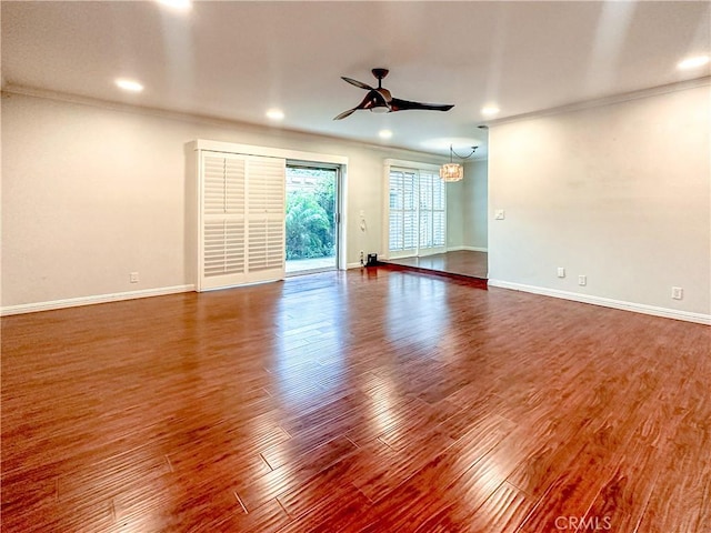 spare room featuring dark wood-type flooring, ceiling fan, baseboards, and ornamental molding