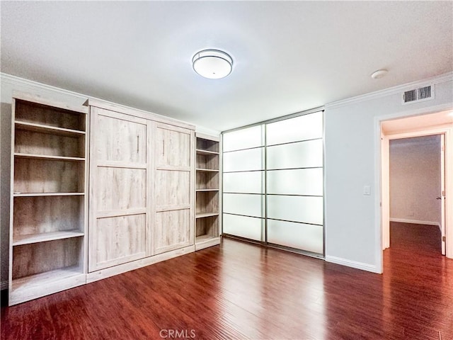 unfurnished bedroom with dark wood-style floors, visible vents, crown molding, and baseboards