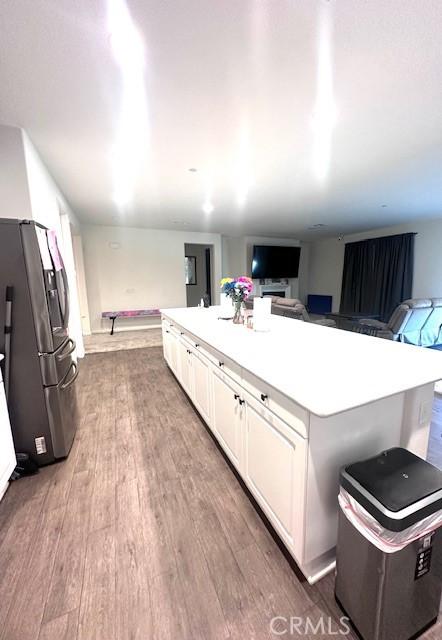 kitchen with white cabinets, dark hardwood / wood-style floors, a kitchen island, and stainless steel fridge with ice dispenser