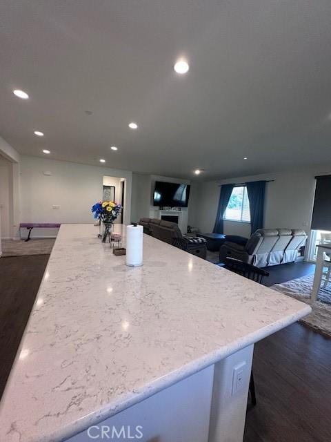 kitchen featuring dark hardwood / wood-style floors, a center island, and light stone countertops