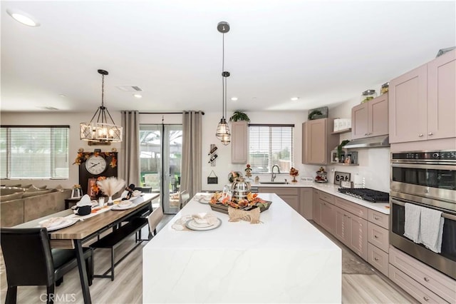 kitchen with an inviting chandelier, a kitchen island, pendant lighting, and light wood-type flooring