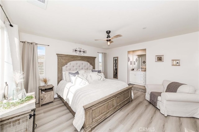 bedroom with connected bathroom, ceiling fan, and light hardwood / wood-style flooring