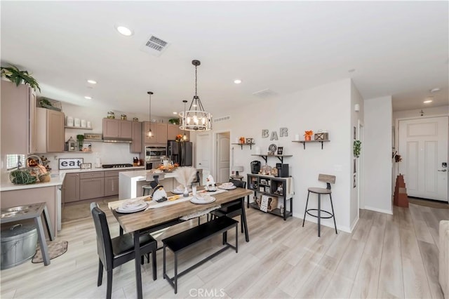 dining space with light wood-type flooring and a chandelier