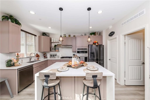 kitchen featuring appliances with stainless steel finishes, a center island, pendant lighting, and sink