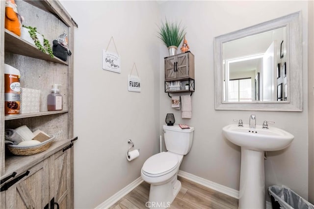 bathroom with toilet, wood-type flooring, and sink