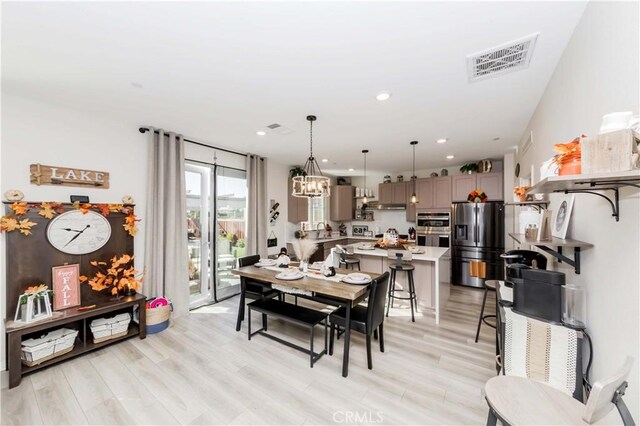 dining room with light hardwood / wood-style floors and an inviting chandelier