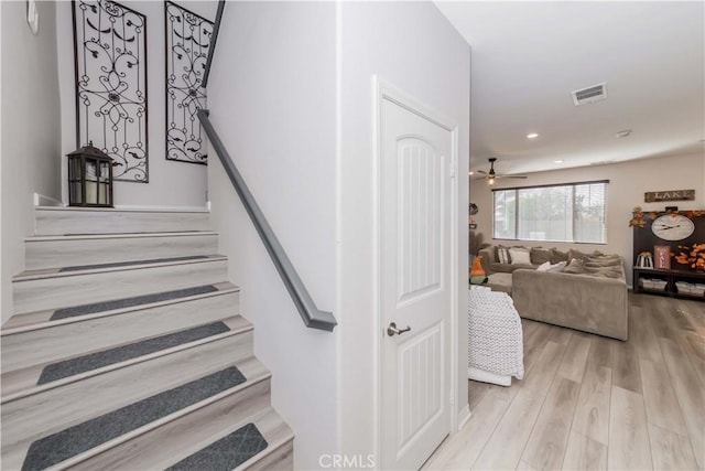 stairway with hardwood / wood-style flooring and ceiling fan