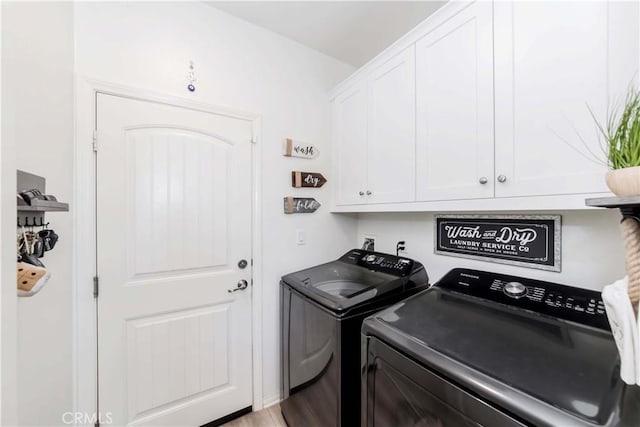 clothes washing area featuring hardwood / wood-style floors, cabinets, and independent washer and dryer