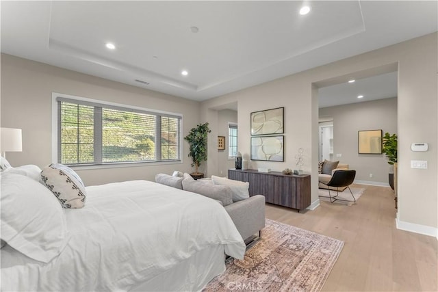 bedroom featuring a tray ceiling and light hardwood / wood-style flooring