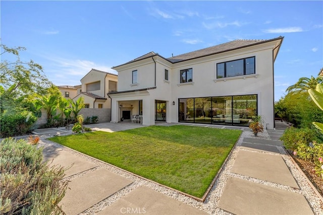 rear view of house with a lawn and a patio