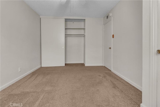 unfurnished bedroom featuring a closet, a textured ceiling, carpet floors, and ceiling fan