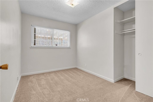 unfurnished bedroom featuring light carpet, a closet, and a textured ceiling