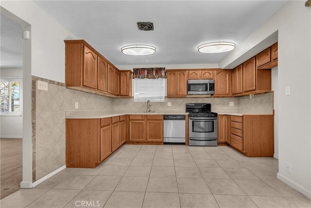 kitchen featuring backsplash, sink, light tile patterned flooring, and appliances with stainless steel finishes