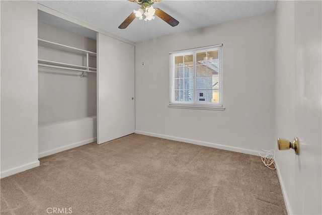 unfurnished bedroom with a textured ceiling, ceiling fan, light carpet, and a closet