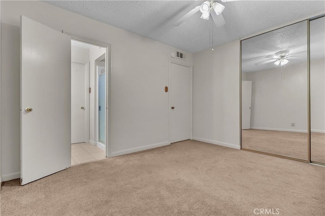 unfurnished bedroom with a textured ceiling, light colored carpet, and ceiling fan