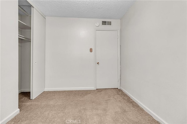 unfurnished bedroom featuring light carpet, a textured ceiling, and a closet