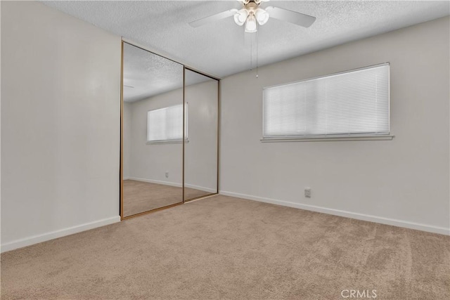 unfurnished bedroom featuring ceiling fan, a closet, and light carpet