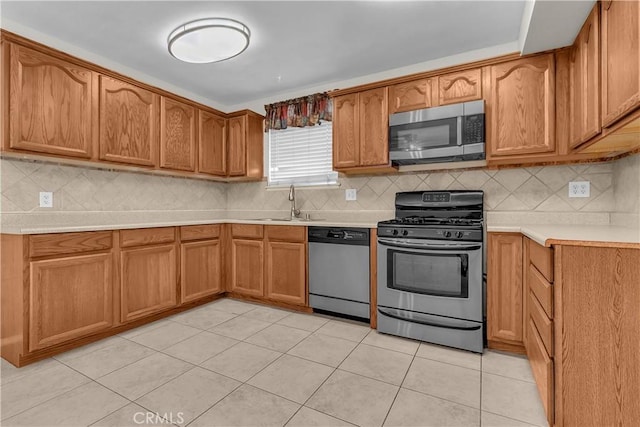 kitchen featuring tasteful backsplash, sink, light tile patterned flooring, and appliances with stainless steel finishes