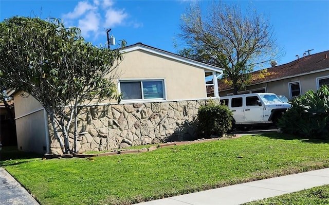 view of side of home with stone siding, a lawn, and stucco siding