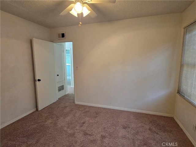 carpeted spare room featuring baseboards, visible vents, and a textured ceiling